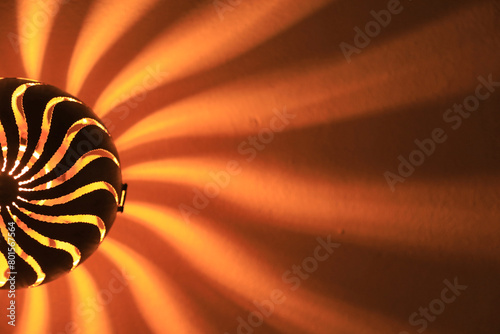 lámpara de pared metálica imitando a un sol haciendo sombras en forma de rayos y fuego 4M0A8141-as24