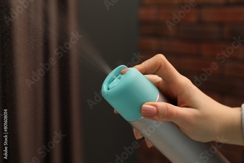 Woman spraying air freshener indoors, closeup. Space for text