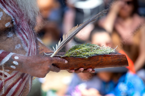 Human hands hold wooden dish with Australian plant branches, the smoke ritual rite at a indigenous community event in Australia 