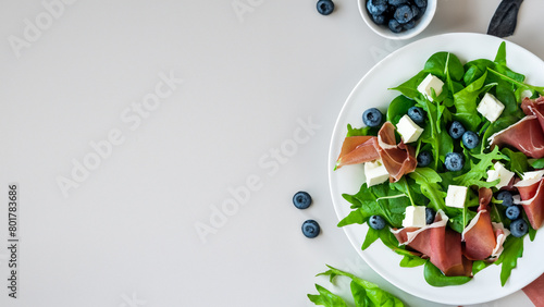 Green salad with arugula, blueberries and feta cheese.Top view on white background. Generative Ai