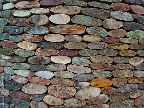 Cut pebble stone texture wall floor colorful background. Wall made from cut pebble gravel stones different shape as floor texture background. Multicolor sliced pebble cut stones wall. Cut stone wall