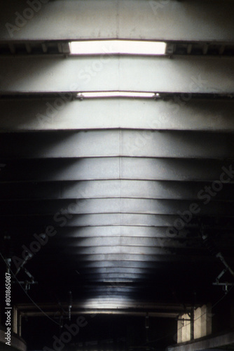 Vertical image of sky lights in roof space. natural sunlight white blurry pattern. black wall space. two small window embrasures with back lighting. Location Euston Railway Station London UK 2003