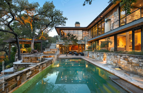 A large pool and house in San Antonio, Texas with a light blue roof. The home is an old stone ranch-style two-story building that has multiple windows and doors on the first floor.