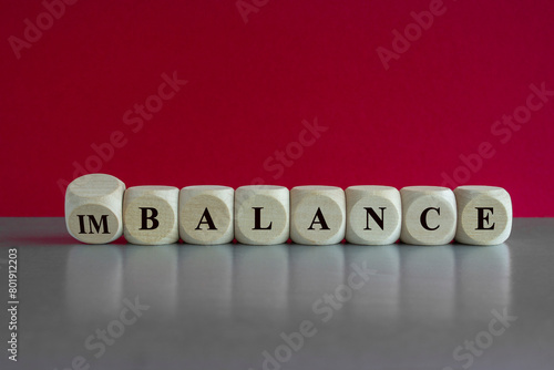 Turned a cube and changes the word imbalance to balance. Beautiful red background, grey table. Business, balance or imbalance concept.