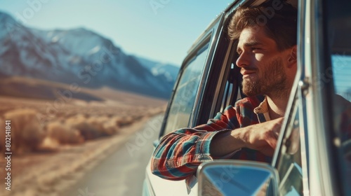 Handsome male tourist looks out of motorist's window and smiles. Road trip in the desert