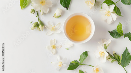 Cup of jasmine tea and flowers on white background