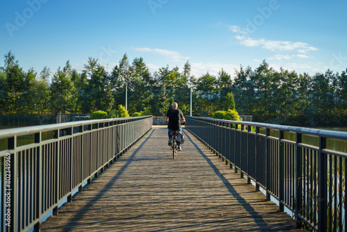 Starszy an jadący rowerem przez molo wieczorem w pogodny letni dzień