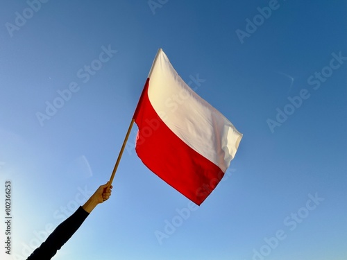 Polska flaga biało-czerwona powiewająca na wietrze na tle błękitnego nieba. Dzień Flagi, Święta Narodowe, 3 Maja, patriotyzm.