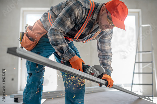 Making a plasterboard ceiling. The worker shortening the CD ceiling profile using the angle grinder. It is wrong work.