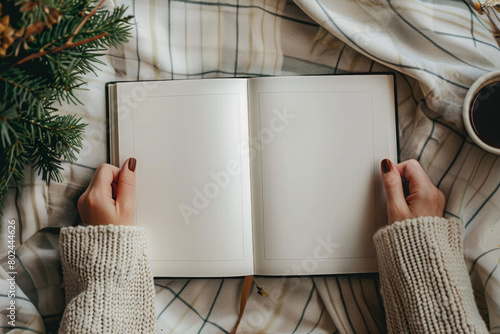 Hands holding an open blank book on a cozy blanket