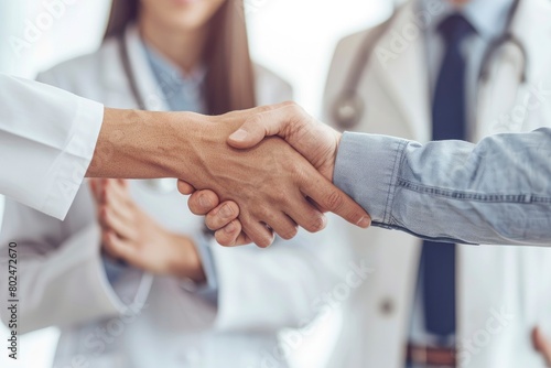 Doctor shaking hands with his patient while the nurse is smiling in front of them