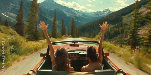 Two girls in a red car with their hands up driving through a valley in summer