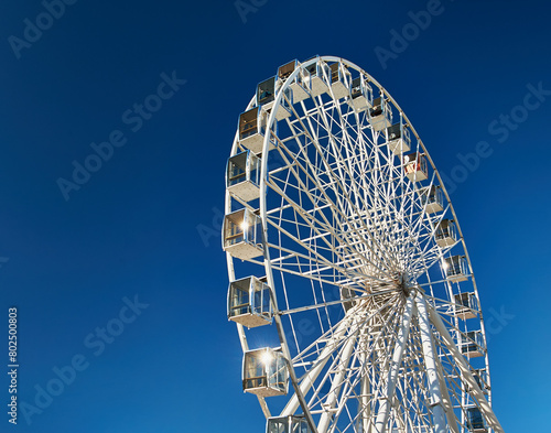 A majestic Ferris wheel stands tall against a clear blue sky. Amusement Park.