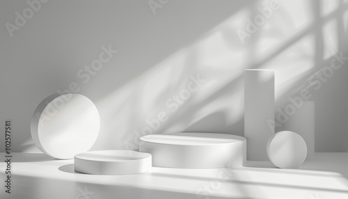 A minimalist composition of white geometric shapes including a sphere, cylinders, and blocks, creating shadows on a plain background with natural light.