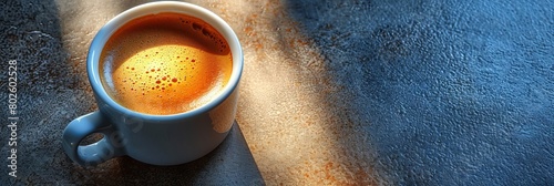 A cup of coffee seen from above on a plain table top. 