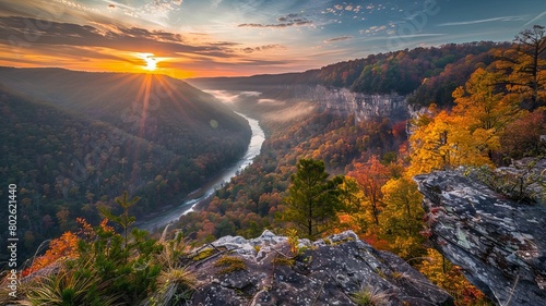 Amazing view of the New River Gorge in West Virginia, with the sun rising over the horizon and the autumn leaves turning the trees a vibrant orange and yellow.