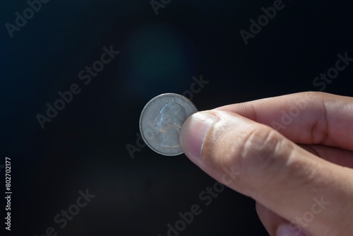 Hand holding an old American quarter dollar coin Liberty 1989 on dark background