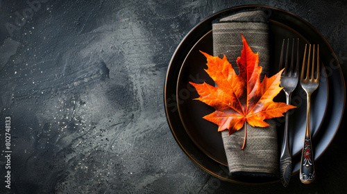 Plate with cutlery napkin and autumn leaf on table