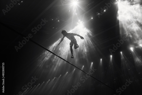 High jumper arching gracefully over the bar, clearing it with ease.A person is tightrope walking in the dark, creating a thrilling atmosphere