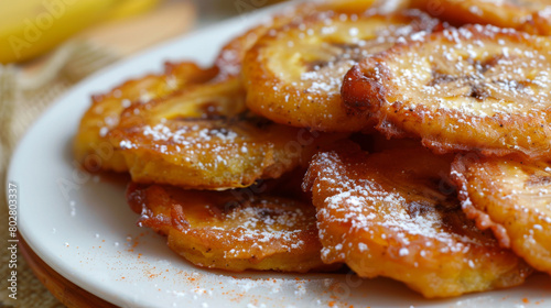 Caramelized fried plantains with powdered sugar, a classic jamaican dessert, presented on a white plate in a close-up shot