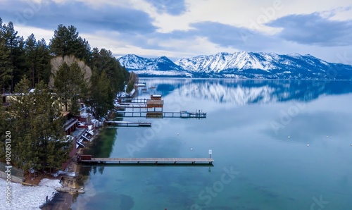 Calm mirror Lake Tahoe, pier and mountains with snow. Tahoe Keys, South Lake Tahoe, California, United States of America.