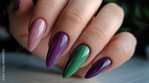 Close-up of a hand with long, almond-shaped nails painted in a gradient of purple and green colors.