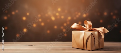 A brown gift box with a ribbon tag and copy space image placed on a wooden background creates an aesthetic composition