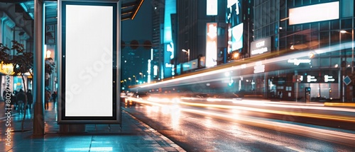 A sleek and modern commercial image showcasing a blank white vertical digital billboard poster on a city street bus stop sign at night