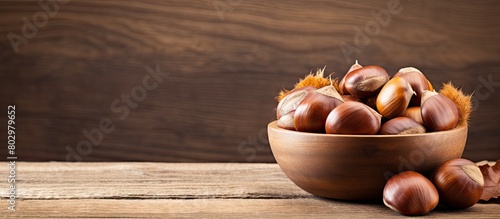 A copy space image showcasing a bowl of fresh chestnuts placed on a rustic old wooden backdrop