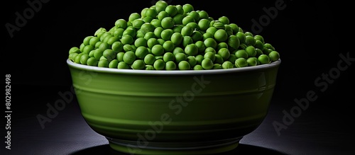 A cup filled with green peas stacked vertically on a black backdrop featuring copy space image