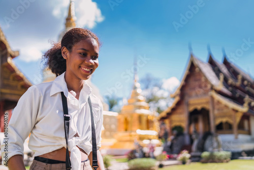 happy black tourist girl taking picture using vintage camera at temple. teenage african american using vintage camera taking temple photo. solo traveler relax doing photo shoot of thailand landmark