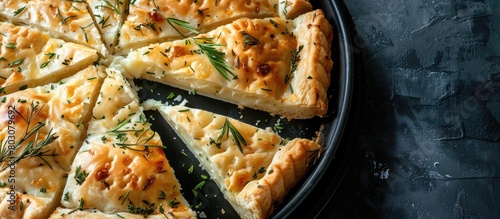 Top view of a kitchen tray filled with slices of Round Borek cheese pie baked with herbs, set against a dark background.