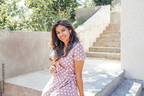 Beautiful young mixed race woman in pink dress smiling and holding glass of champagne.