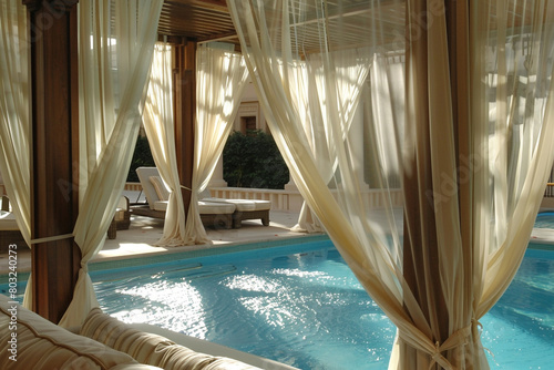 A luxurious pool cabana, draped with sheer curtains billowing in the gentle breeze.