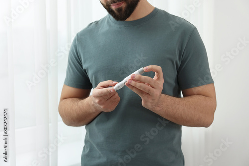Diabetes test. Man checking blood sugar level with lancet pen at home, closeup