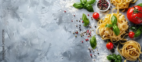 Top view of uncooked pasta and vegetables with copy space in the background. Italian pasta, tomatoes, basil, and spices, representing the concept of Italian cuisine.