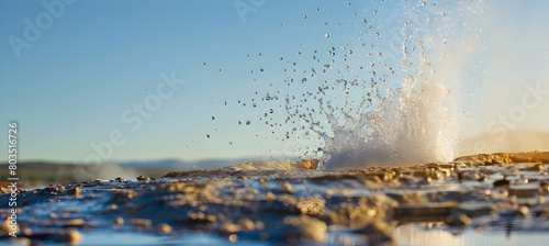 Close-up of a powerful geyser eruption, capturing the dynamic splash and intricate water droplets in mid-air, set against a clear blue sky