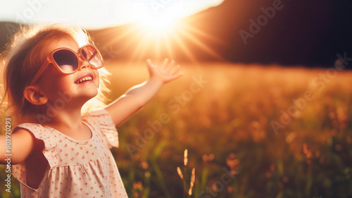 Happy little girl with sunglasses looking at the sun