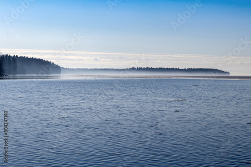 Morning spring fog near the horizon of the water surface of the large Onega Lake in Karelia.
