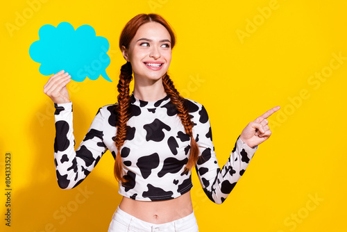 Photo of sweet cute lady dressed cowskin print top holding speaking bubble showing empty space isolated yellow color background