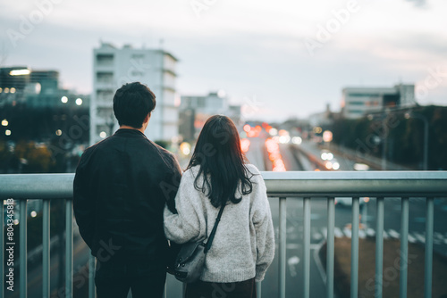 歩道橋から夜景を眺めるカップルの後ろ姿