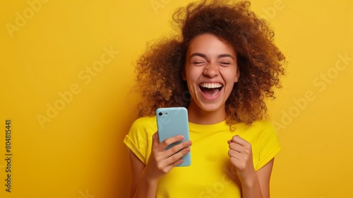 Exuberant young woman with curly hair celebrating exciting news on a smartphone, Concept of joy and communication technology