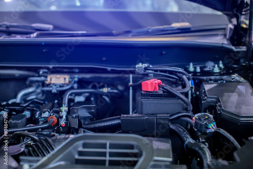 Selective focus to battery anode in the hybrid automotive car engine room. Red plus pole battery.