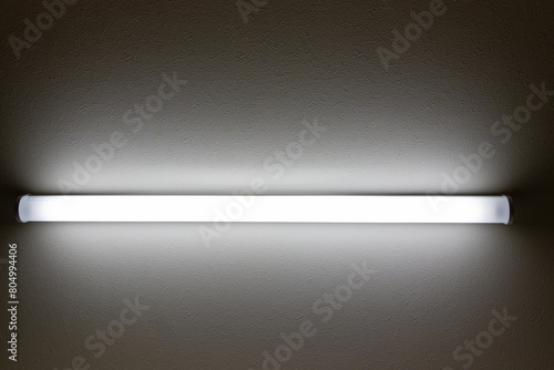 暗い部屋の中で点灯する直管型の照明器具 