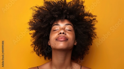 Upbeat woman with afro hair looking upwards on a neutral background