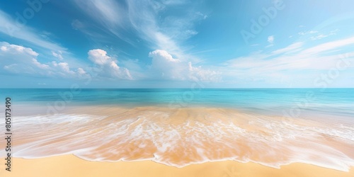 Beautiful natural tropical summer beach background with golden sand, turquoise ocean, and blue sky with white clouds.
