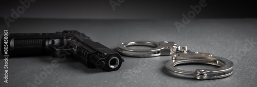 Gun and handcuffs on gray background, stock photo, criminal concept