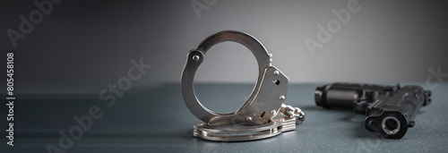 Gun and handcuffs on gray background, stock photo, criminal concept