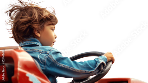 Mały chłopiec o jasnych włosach prowadzi zabawkowy samochód za pomocą kierownicy. Jest skoncentrowany na zabawie i bawi się z uśmiechem na twarzy