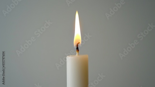  A candle with a white base and a yellow candle inserted vertically through its center, topped by another single candle